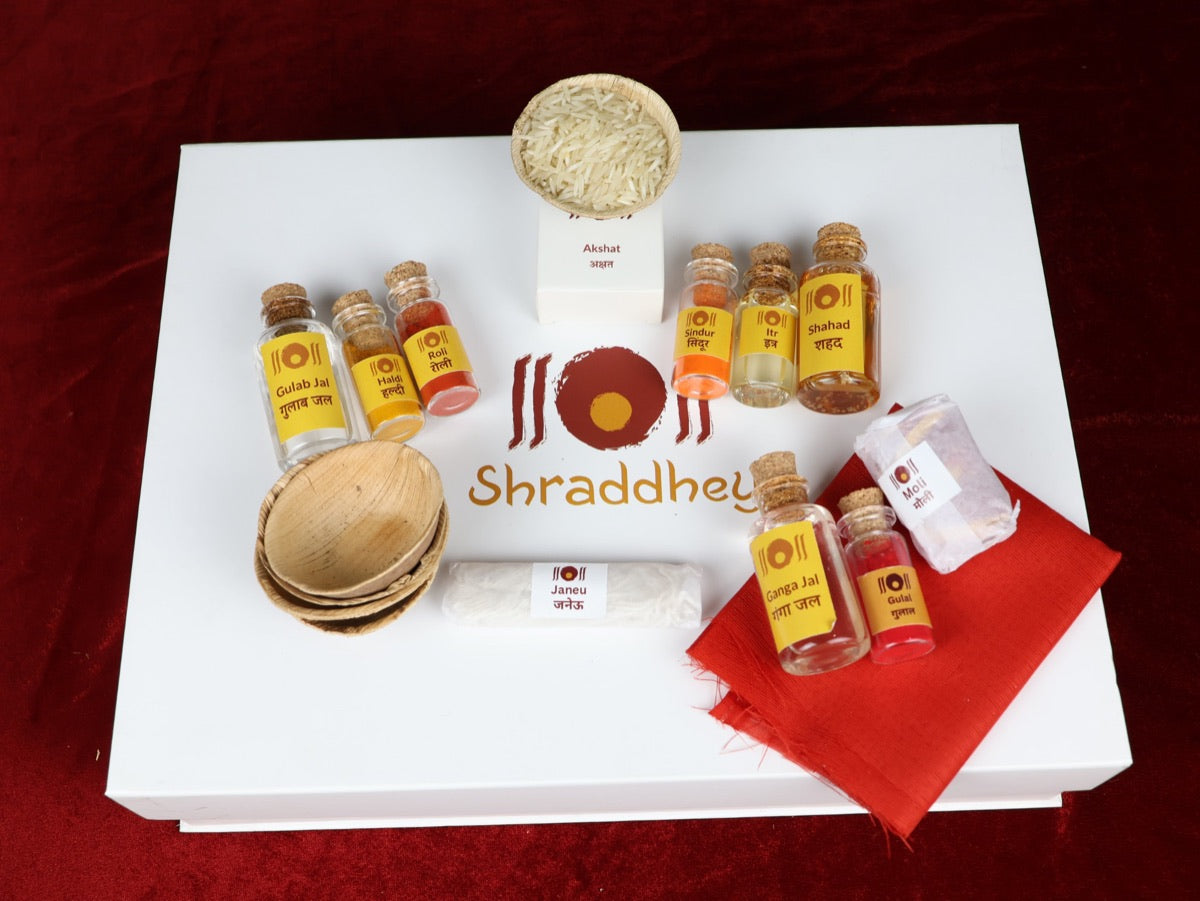 Shringar items from the box: Ganga Jal, Gulab Jal, Shahad, Roli, Haldi, Sindur and Itra vials, Akshat in a leaf bowl, Gulal, Moli, Janeu, leaf bowls and red cloth
